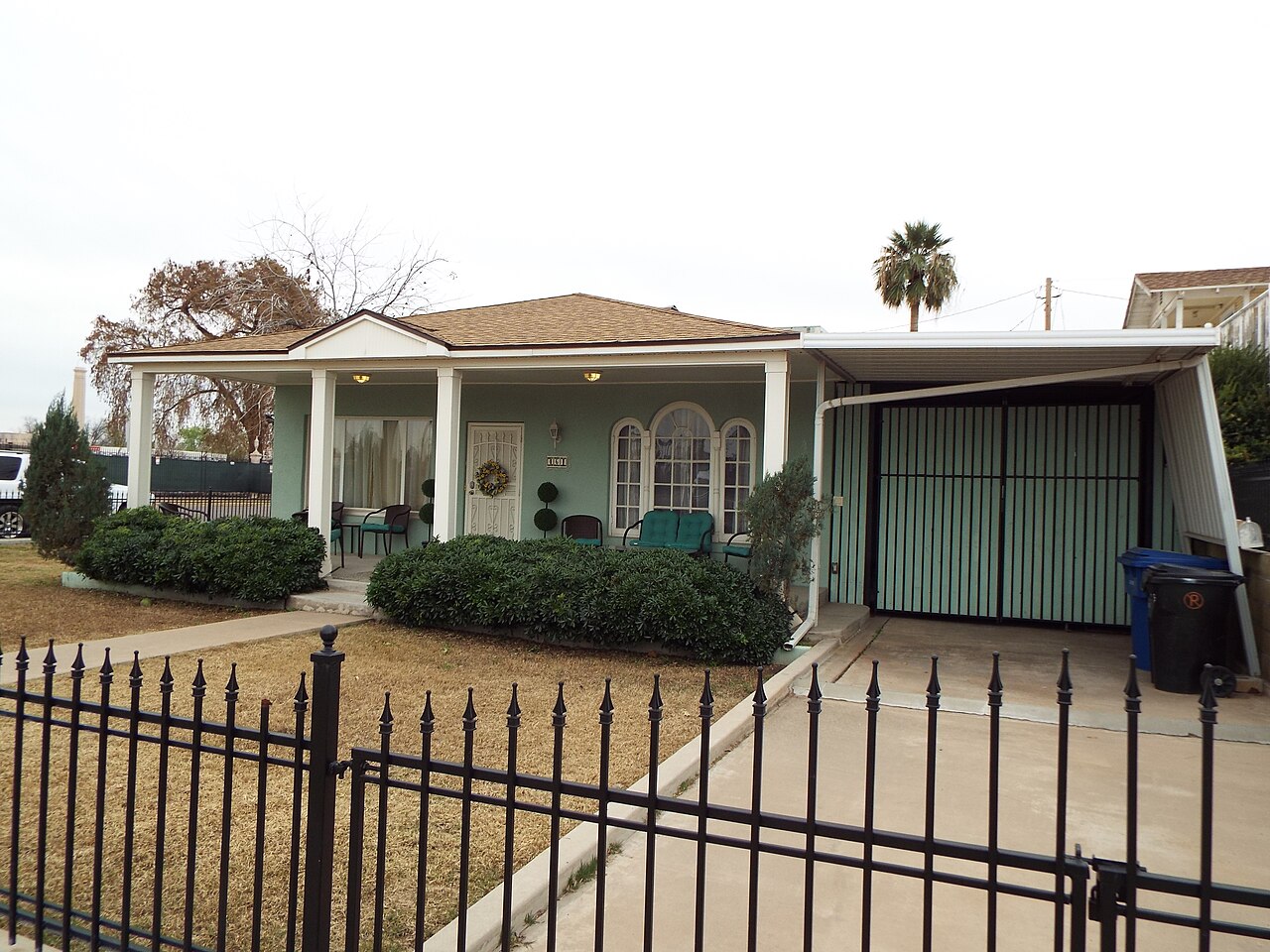 Modest 1930s cottage with a carport and palm tree in Mesa, Arizona